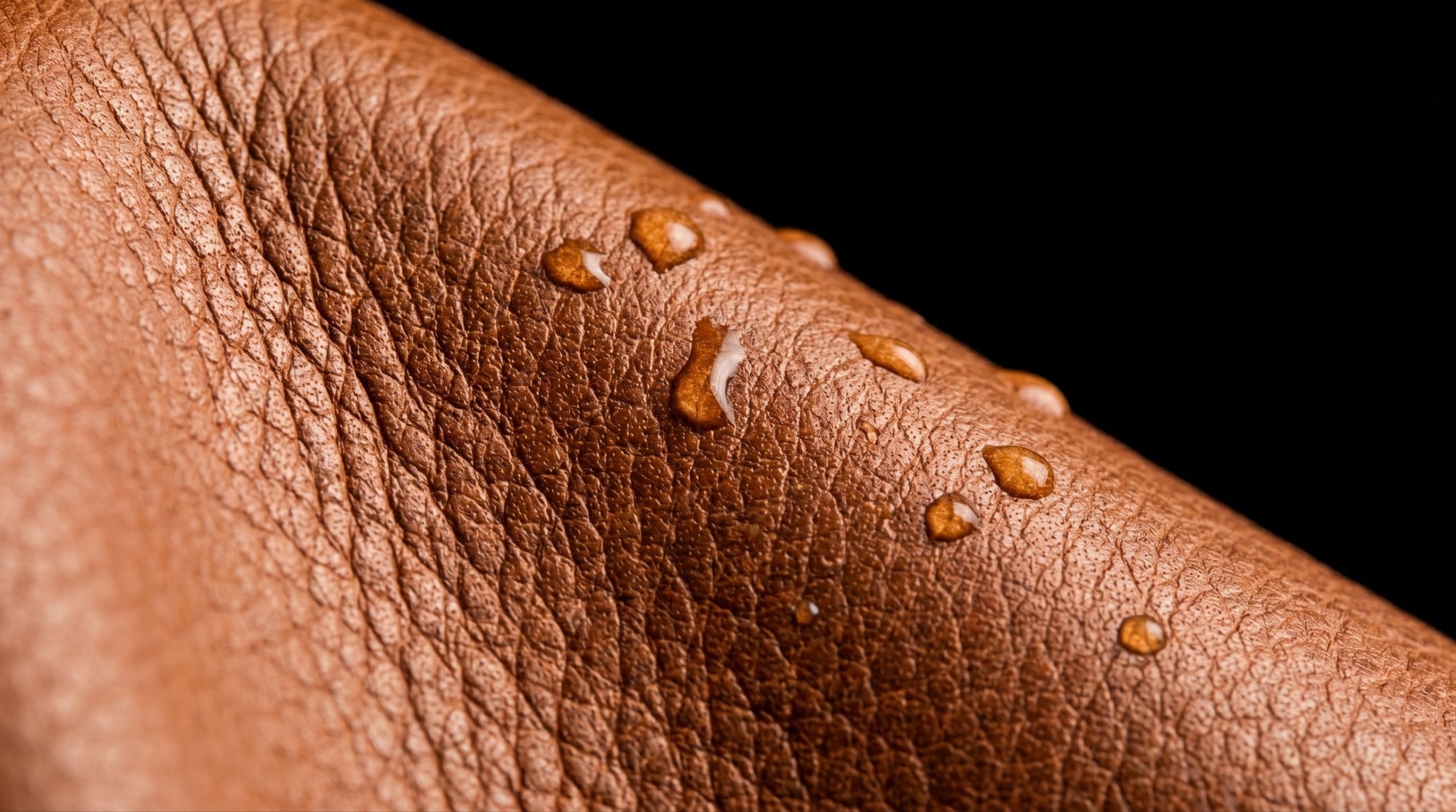 Macro close-up del grano entero de piel italiana color cognac con aceite acondicionador